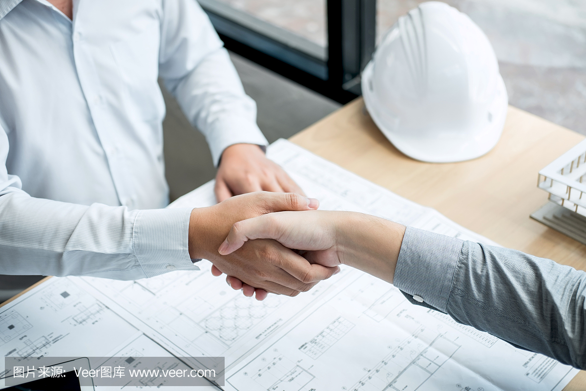 合作伙伴握手,建筑工程或建筑師討論藍(lán)圖和建筑模型,同時檢查草圖信息,為建筑項(xiàng)目的合作伙伴舉行會議